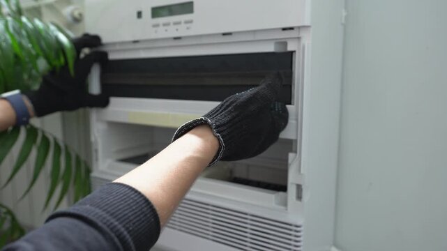 Hands in black gloves removing an air filter from the air purification system. Close-up.
