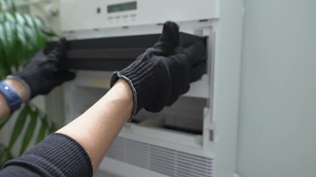 A close-up of the new air filter. A woman&rsquo;s gloved hands are fitting the air filter for the indoor air purification system.