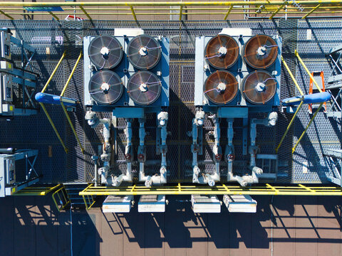 Aerial view of data center HVAC thermal management and cooling fans on a rooftop with industrial piping and metal grating in Andover, England, United Kingdom.
