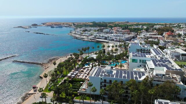 Drone view of Paphos seafront in Cyprus. Resort buildings, coastal road, blue Mediterranean water and beach area create a sunny city coastline panorama.