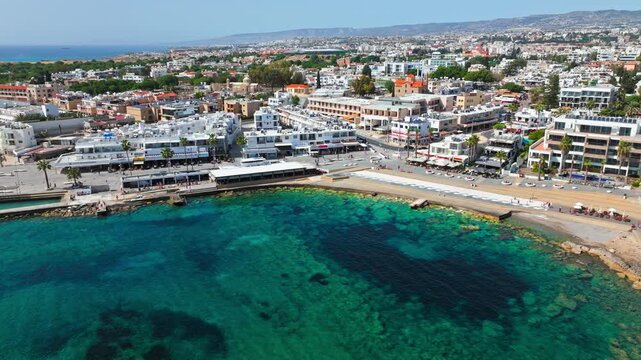 Drone view of Paphos coastal resort area in Cyprus. Clear turquoise sea, shoreline hotels and waterfront streets create a scenic Mediterranean panorama.