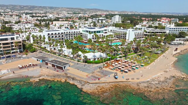 Aerial view of Paphos seafront in Cyprus. Sandy beach, resort hotels, turquoise water and coastal promenade create a sunny holiday destination scene.