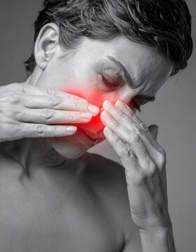 Woman holding both hands over her face suffers from intense sinus inflammation and pain.