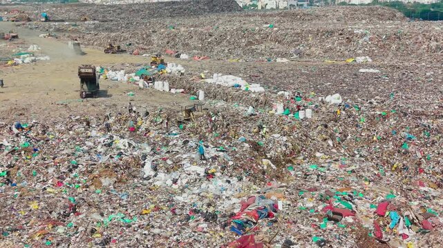 Crane pushing and segregating garbage across an active waste dump yard