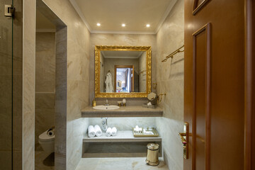 Obraz premium Elegant hotel bathroom interior with golden mirror and white towels
