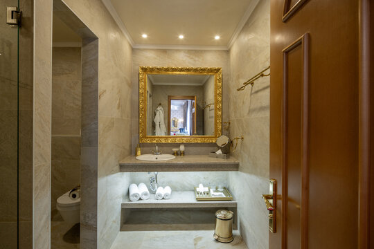 Elegant hotel bathroom interior with golden mirror and white towels