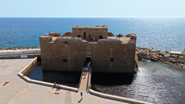 Drone view of Paphos Castle at the harbour in Cyprus. The medieval fortress, stone bridge and surrounding sea create a scenic historic landmark view.