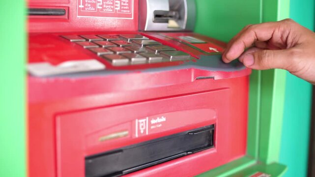Man using keypad on automatic telling machine for withdrawing money with finger pressing numbers to enter security pin code in 4K Ultra HD footage
