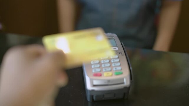 Point of view of man using credit card on modern wireless terminal for fast financial transaction in slow motion in 4K Ultra HD footage
