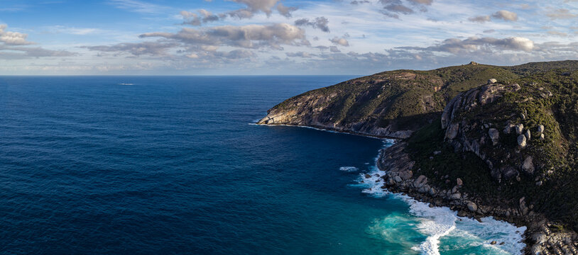 Aerial view of the rugged coastline at Salmon Holes, featuring granite cliffs, turquoise waves crashing against the shore, and deep blue ocean in Torndirrup, Western Australia, Australia.
