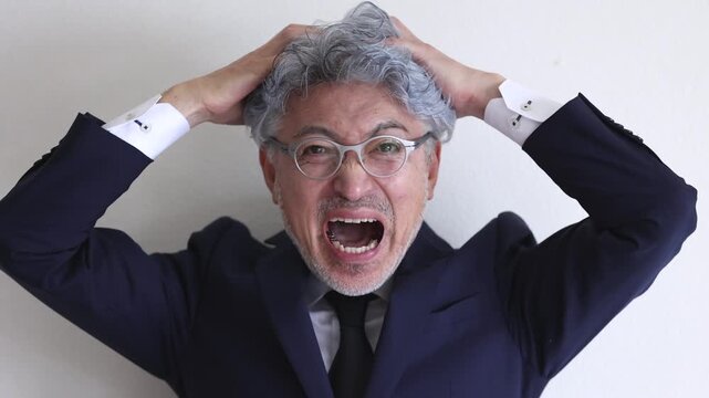 頭を抱えて叫ぶストレスを感じた中高年の男性ビジネスマン