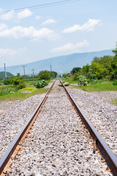 Railroad Tracks Crossing Green Countryside in Colima Mexico Toward Distant Mountains