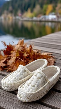 Traditional bast shoes on a wooden platform with autumn leaves and blurred greenery in the background