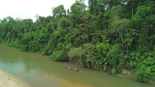 Drone following a traditional longboat along Sungai Tembeling through primary tropical rainforest, Al-Sultan Abdullah Royal Tiger Reserve, Pahang, Malaysia