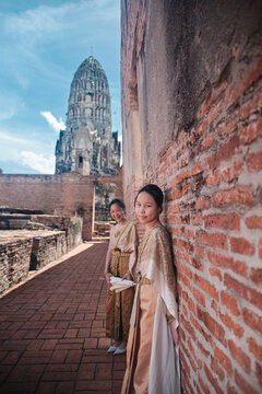 Asian family, mother and child dressed in Thai traditional outfit with cheerful smiles and looking at camera, holiday travel in Ayutthaya, Southeast Asia, ancient ruins heritage,  tourist destination.