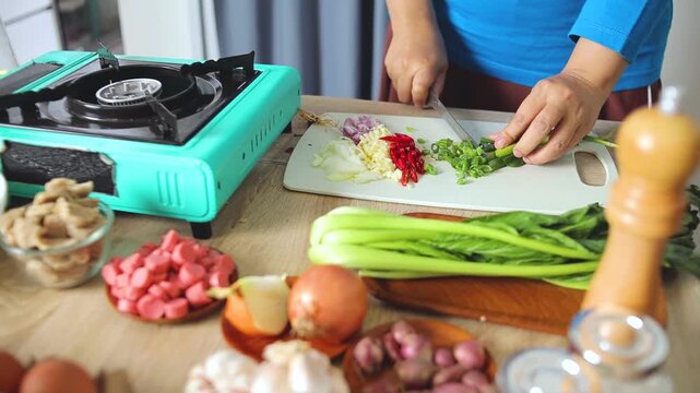 Chef chopping spring onions during food preparation in kitchen