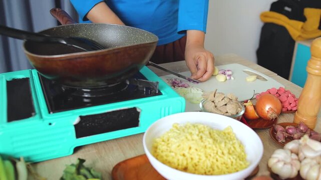 Kitchen scene showing hands slicing shallots on cutting board