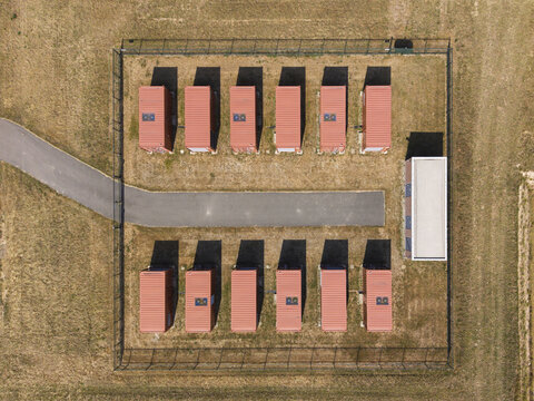 Aerial view of a battery system with rows of red storage containers and a small building inside a fenced area in Middelharnis, South Holland, Netherlands.