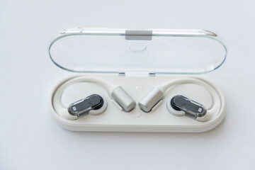 Fototapeta premium Wireless open ear headphones in charging case on white surface