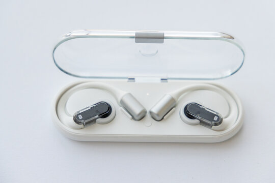 Wireless open ear headphones in charging case on white surface
