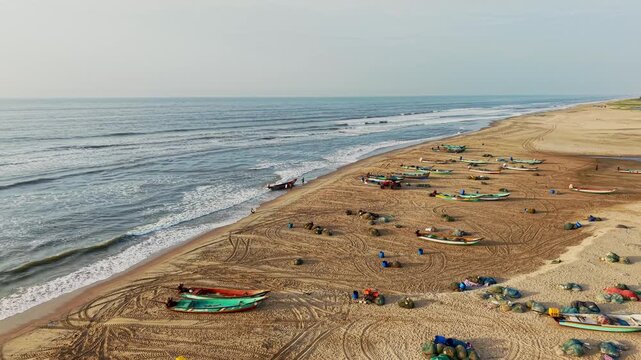 Aerial drone shot of Bay of Bengal waves rolling onto Chennai beach where fishing boats rest along the sandy coastline in Tamil Nadu, India