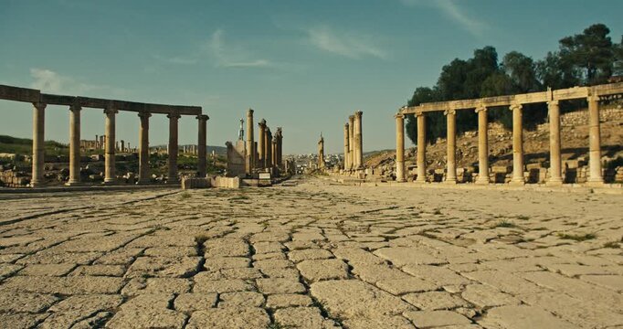 Low angle view of the ancient stone paved street and Roman colonnade in Jerash, Jordan. Historic archaeological site showcasing classical architecture, cultural heritage, preserved ruins in daylight