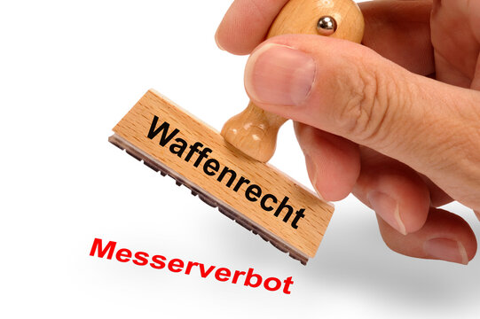 Ein Holzstempel ist beschriftet mit dem Aufdruck: Waffenrecht und dem Abdruck Messerverbot