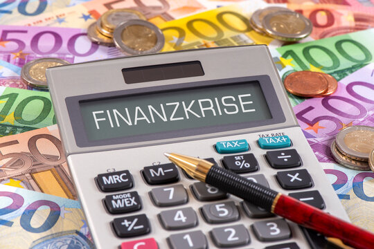 Auf vielen Euroscheinen liegt ein Taschenrechner mit dem Wort Finanzkrise im Display - FOTOMONTAGE