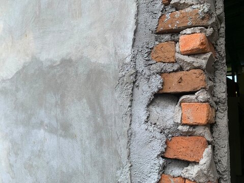 Exposed red clay bricks set in rough grey cement mortar wall