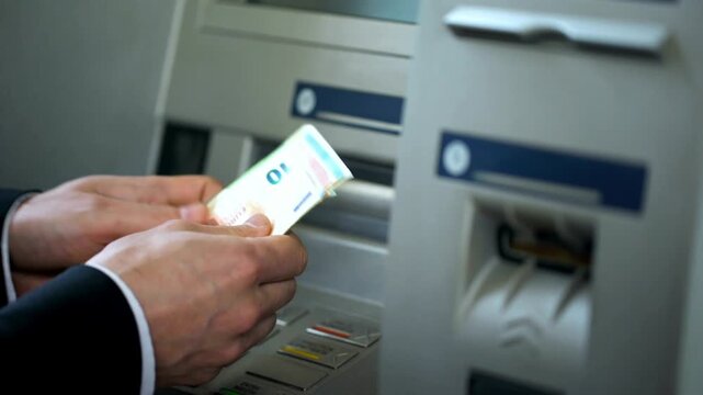 Man counting euros withdrawn from ATM machine and putting cash in wallet for convenience and secure banking transaction in 4K Ultra HD footage

