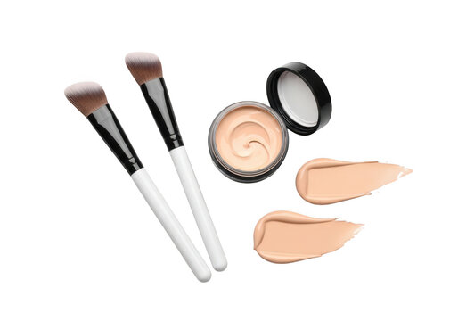 Two angled makeup brushes with white handles, a small open jar of beige liquid foundation, and two smooth cream texture swatches isolated on a black background