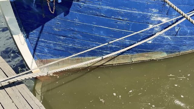 Blue Wooden Boat Hull Moored at Dock with Mooring Ropes