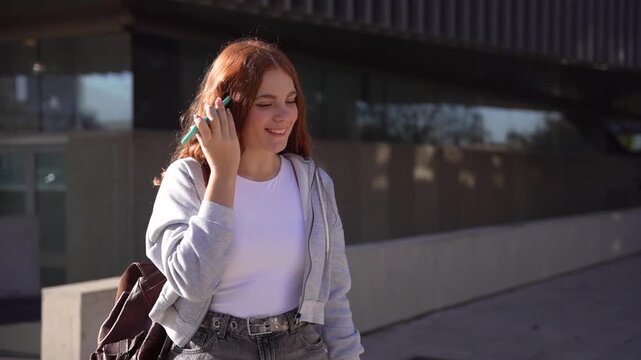 A joyful woman talks on her phone outdoors, enjoying the warm sunshine on a casual day
