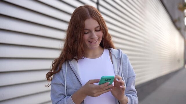 A young woman with a smartphone in an urban setting seems deeply engaged in her surroundings