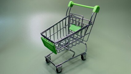Miniature shopping cart with green accents isolated on a plain background, symbolizing retail purchases and consumer spending © MR HEPPY