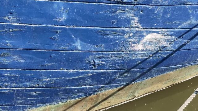 Close-up of Weathered Blue Boat Hull and Rope at Waterline