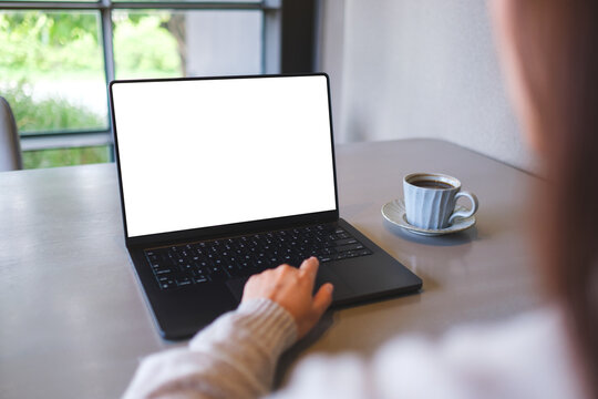 Mockup image of a woman working on laptop computer with blank white desktop screen while drinking coffee in cafe
