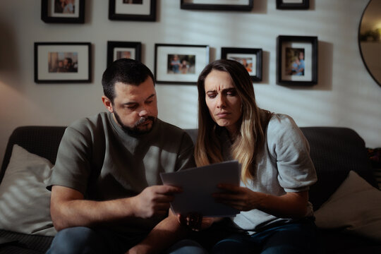 Worried Wife And Husband Frowning While Reading Difficult Financial Bill. Anxious married couple reviewing expensive household utility bills feeling stressed about money problems