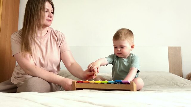 Two year old boy playing xylophone at home. Tapping colorful keys develops fine motor skills and musical ear. Early childhood education through rhythm and sound exploration
