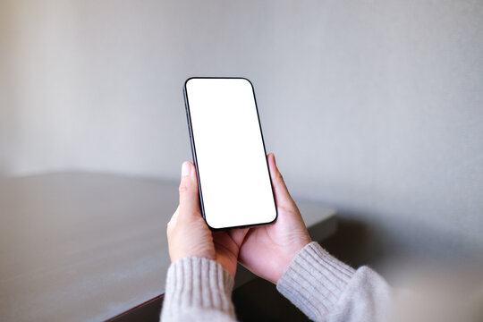Mockup image of a woman holding mobile phone with blank desktop screen