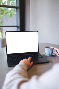 Vertical mockup image of a woman working on laptop computer with blank white desktop screen while drinking coffee in cafe
