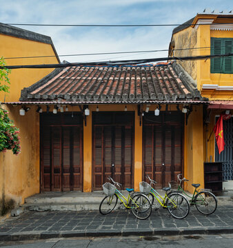 Traditional yellow house with wooden shutters and bicycles in Hoi An Ancient Town, Vietnam