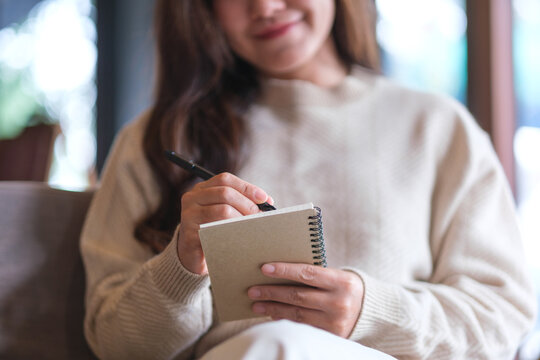 Closeup image of a woman holding and writing on a notebook
