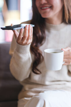 Vertical closeup of a woman holding smart phone and using voice messaging, talking with ai assistant for Artificial intelligence concept