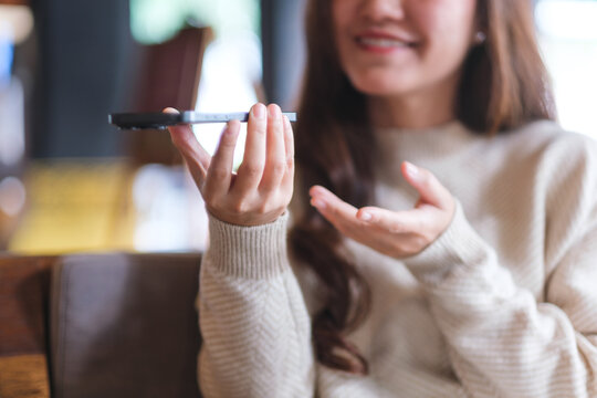 Closeup of a woman holding smart phone and using voice messaging, talking with ai assistant for Artificial intelligence concept