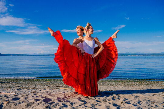 Two white women performing partner acrobatics on a beach in WA, USA