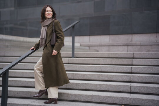 オリーブのウールコートで冬の屋外階段を上る日本人女性