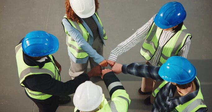 Above, construction and team circle with fist bump for support, motivation and solidarity at job site. People, engineering group and huddle with hands together for unity, workforce goals and trust