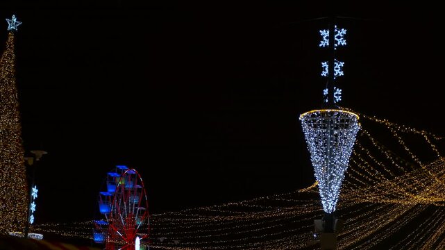 Christmas market lights decoration and ferris wheel at night. Festive christmas market showcasing sparkling holiday decorations, a brilliantly lit christmas tree, and a colorful rotating ferris wheel