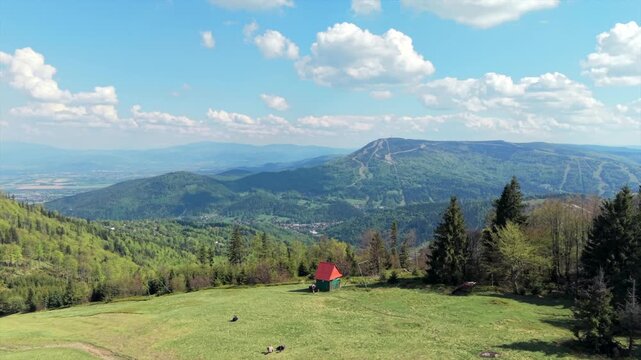 Aerial drone shot flying forward over Klimczok mountain in the Beskids, Poland, passing above forested peaks and valleys toward the horizon under clear sky